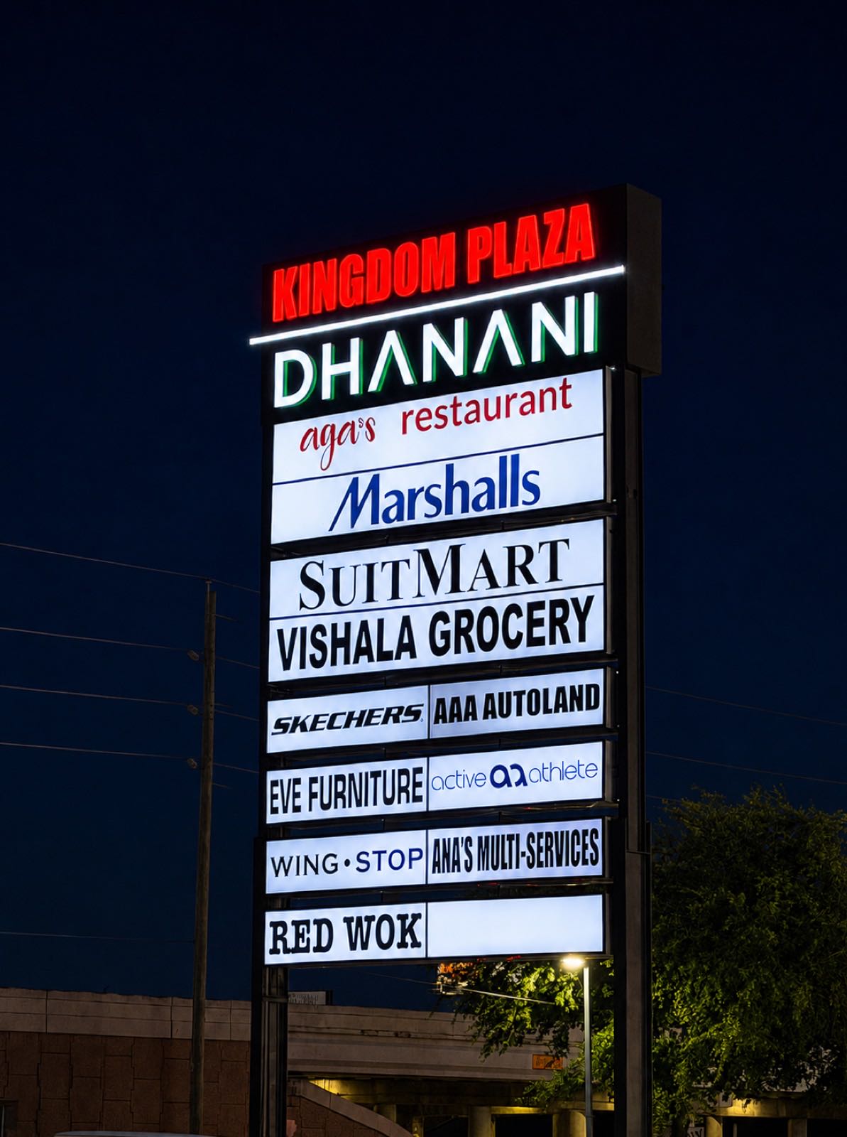 Illuminated multi-tenant pylon sign for Dhanani Plaza at night