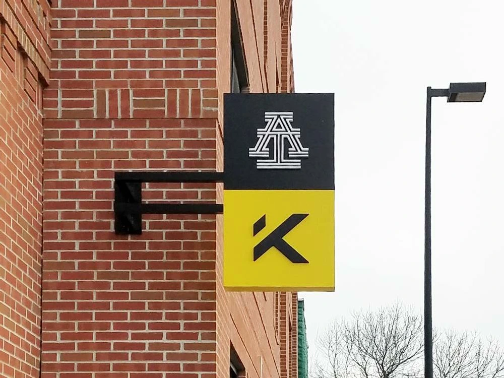 Black and yellow blade sign mounted on a brick wall