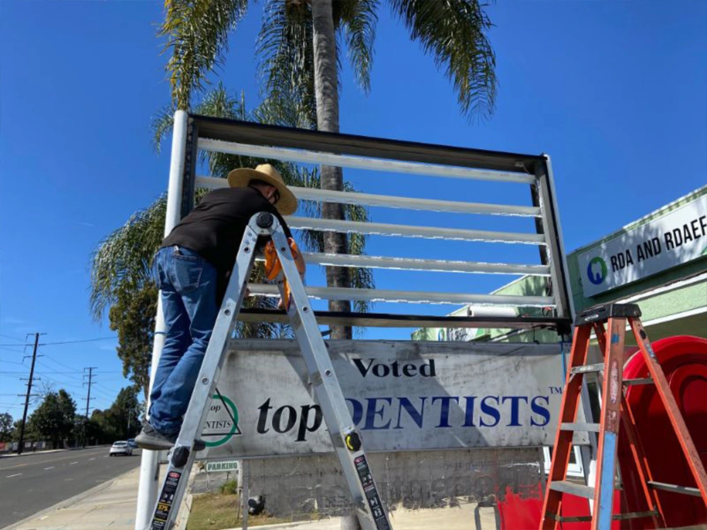 Technician on a ladder replacing a sign face